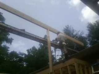 Carpenter setting a ridge beam over a new addition frame — Ice Dam Removal by Roofing Brothers in Franktown