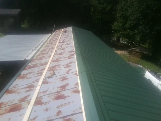 Old rusted panels beside newly installed green metal roofing — Wind Damage Roof Repair by Roofing Brothers in Franktown