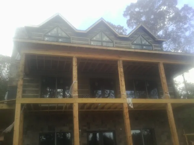 Dormers and porch framing on a large log home under construction — Roof Coating work by our crew in Franktown