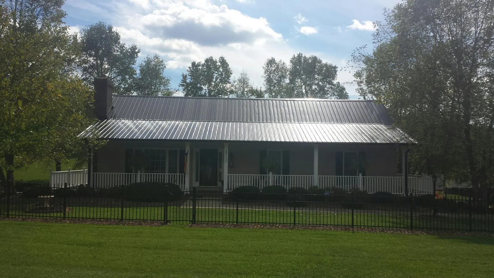 Gray metal roof on a brick ranch with a full width front porch — Gutter Guard Installation work by our crew in Franktown