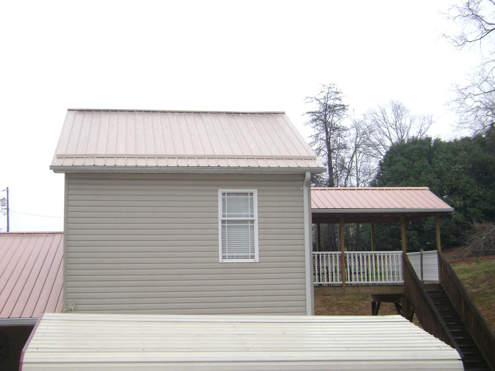 Tan metal roofs on a two story addition and attached porch, from a Roof Replacement job in Franktown